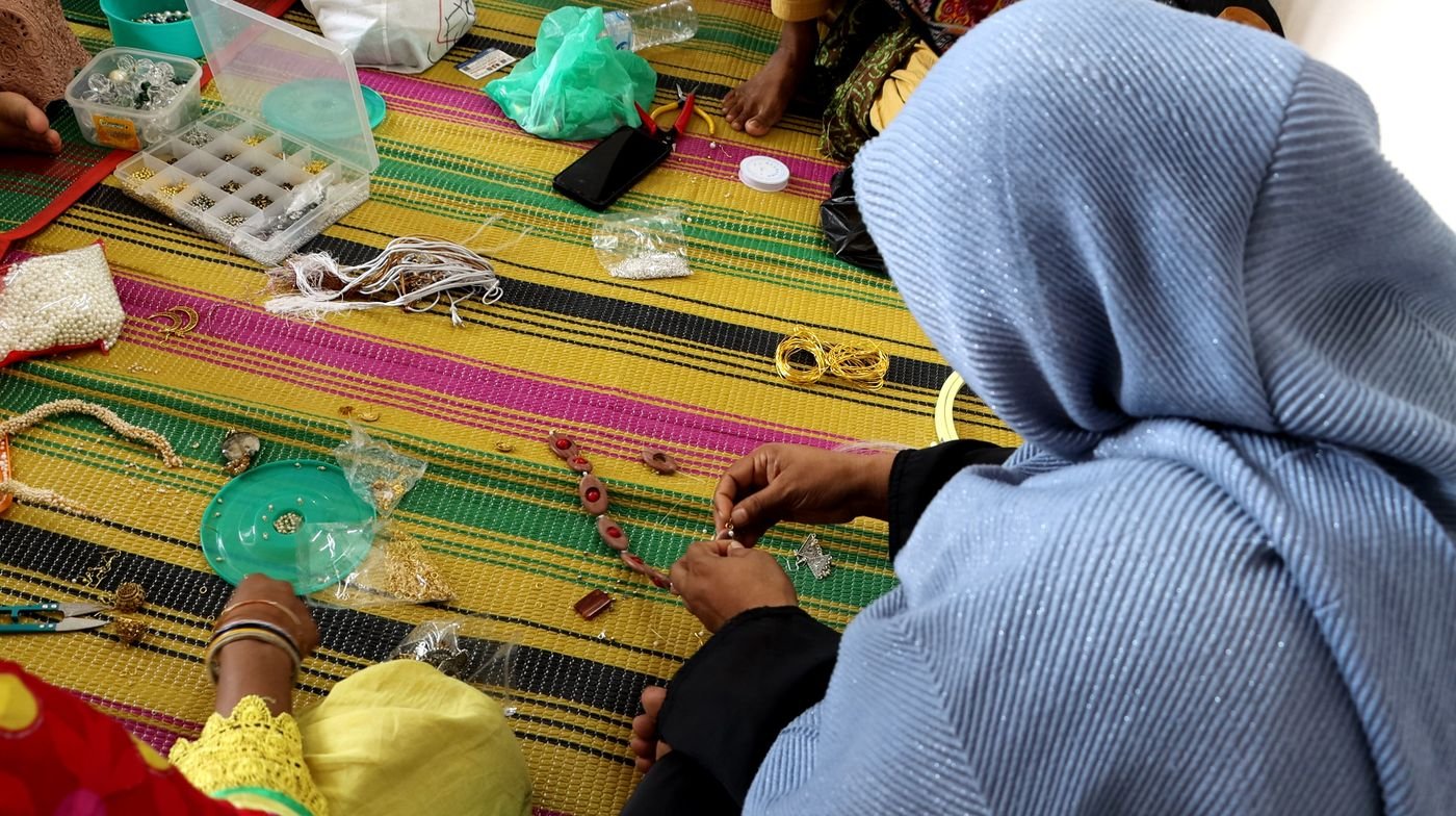 Close-up of a maker learning beadwork, with trays of beads on the mat