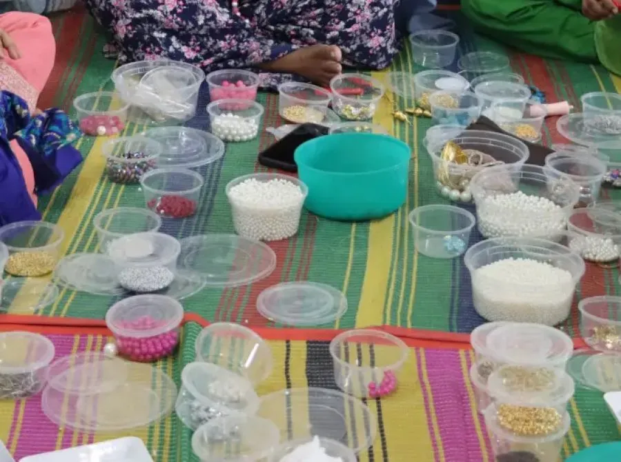 Tubs of beads spread across a striped floor mat in the middle of a work circle