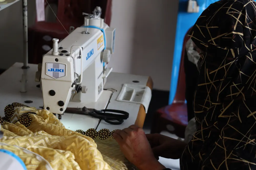 An artisan stitching gold trim on a sewing machine